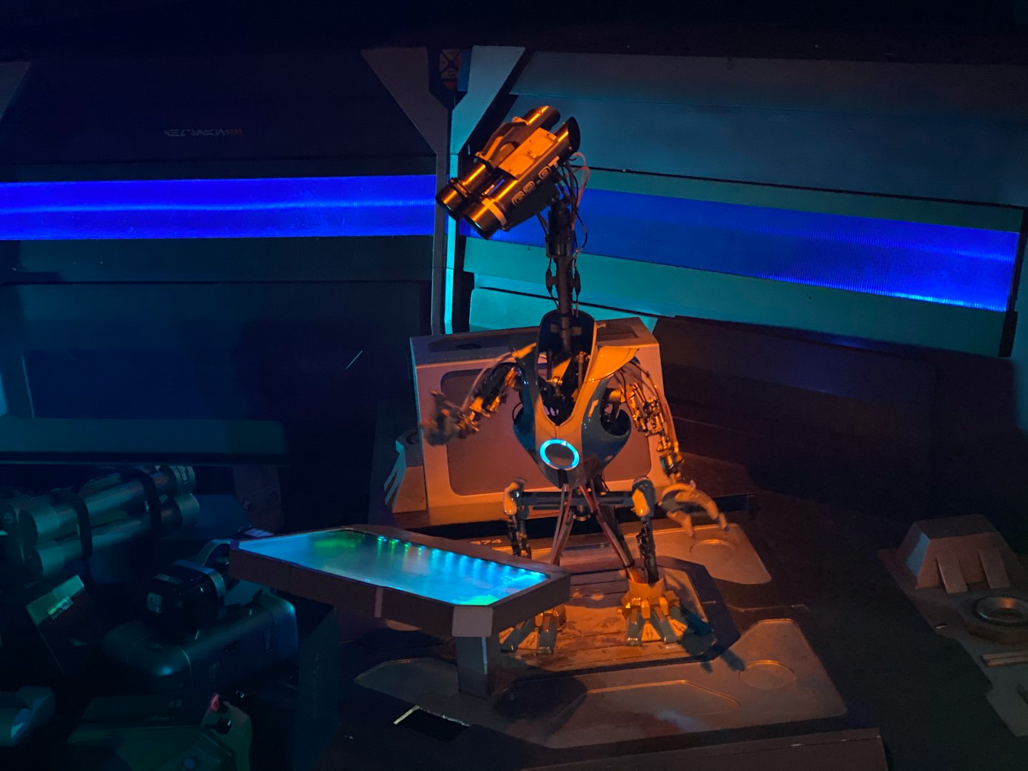 Humanoid robot with blue chest light in a futuristic workshop.
